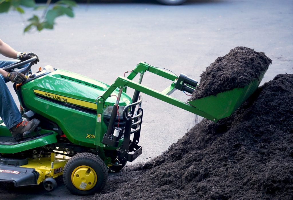 LGM-100 front-end loader scooping mulch on a John Deere lawn tractor